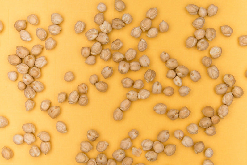 Raw chickpeas displayed on yellow backdrop