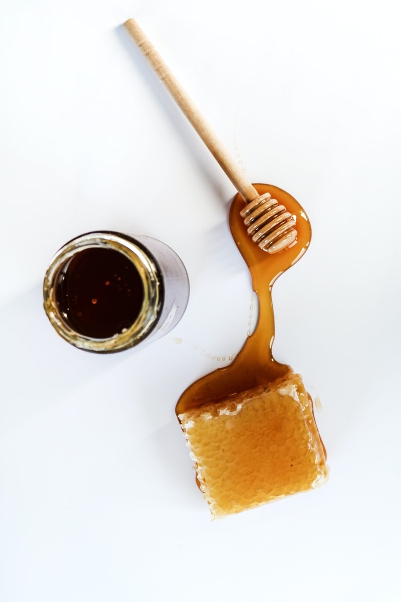 Raw honey from the comb spilled all over a white table