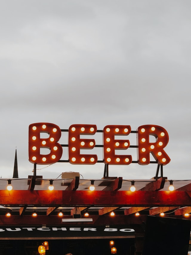 Beer light bulb sign lit up on a cloudy day