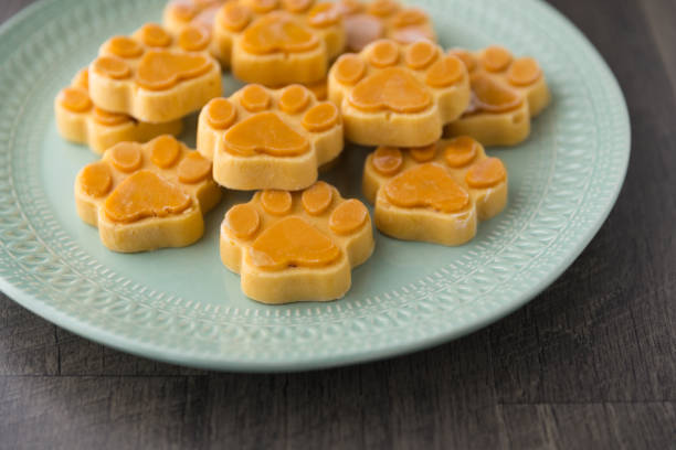 Light blue plate full of orange frozen dog treats shaped as paw prints