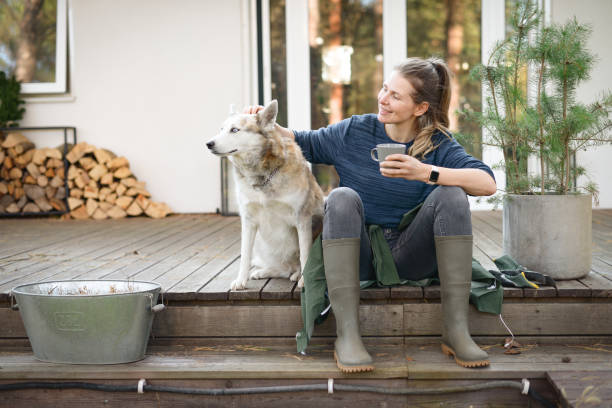 Woman petting her husky out on the front porch while holding a cup of coffee
