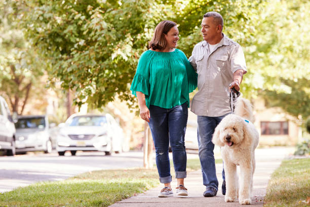Older couple walking their poodle on leash on a nice day in the neighbourhood
